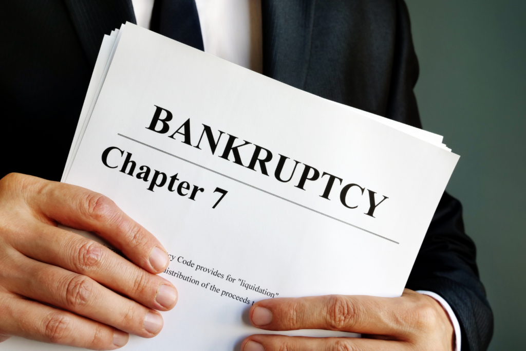 Man in a suit holding Chapter 7 bankruptcy paperwork — representing a co-owner filing affecting Michigan condominium assessment collections.